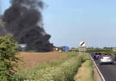 An image of the blazing combine harvester which blocked traffoc on the A153 between North Kyme and Anwick on Wednesday evening. Photo: Geoff Bates EMN-200521-105245001