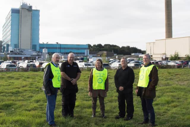 Members of the Rotary Club of Boston discuss the campaign at the current helipad patch of grass at Pilgrim Hospital.