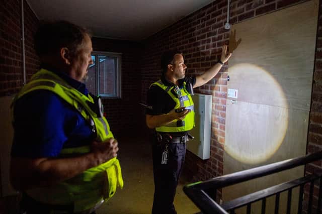 PC Green and PCSO Nigel Wass investigate a boarded up flat. EMN-211021-110039001