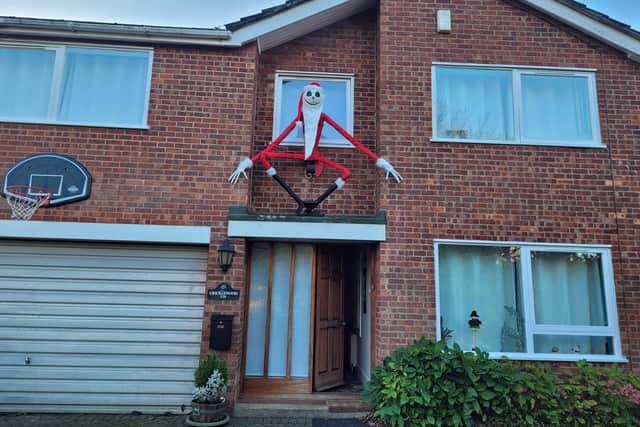 The creepy character looms over the doorway of the house.