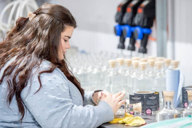 Annabel Cumberworth labelling gin bottles at Massingberd-Mundy. EMN-211216-141913001