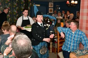 Addressing the Haggis is John Mackenzie.  Kirsteen Macdonald of RAF Waddington pipes and drums, and apprentice chef Blue Charles carrying the haggis. EMN-220126-102619001