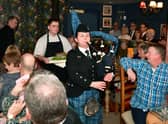 Addressing the Haggis is John Mackenzie.  Kirsteen Macdonald of RAF Waddington pipes and drums, and apprentice chef Blue Charles carrying the haggis. EMN-220126-102619001