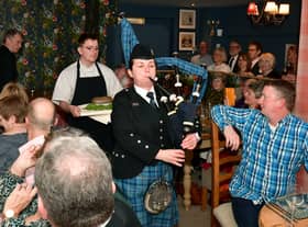 Addressing the Haggis is John Mackenzie.  Kirsteen Macdonald of RAF Waddington pipes and drums, and apprentice chef Blue Charles carrying the haggis. EMN-220126-102619001