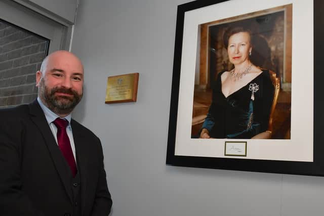 PCC Marc Jones next to a picture of the Patron of The International Police Association, Princess Anne, and the plaque which celebrates her opening the new training centre.