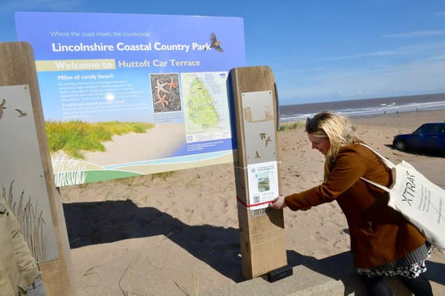 Chelsey Everatt -, producer of Audio Tails, demonstrates how to use the barcodes on the beach at Huttoft, which is one of 24 locations around East Lindsey.
