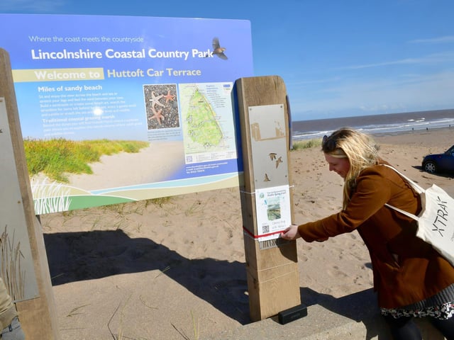 Chelsey Everatt -, producer of Audio Tails, demonstrates how to use the barcodes on the beach at Huttoft, which is one of 24 locations around East Lindsey.