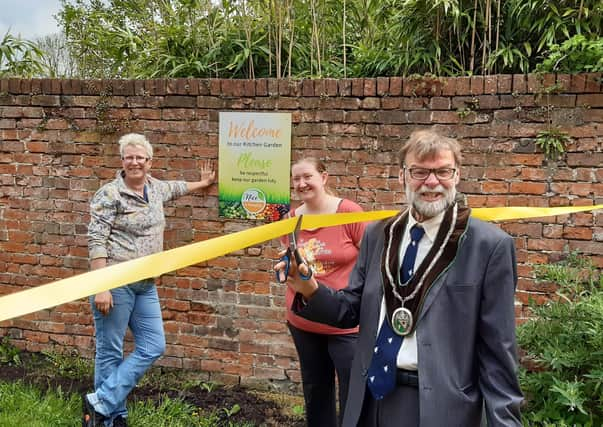 Coun Stephen Bunney cuts the ribbon to officially open the kitchen garden, watched by Cathy Sirrett, left, and Nicky Brooksbank EMN-210518-102144001