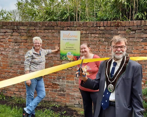 Coun Stephen Bunney cuts the ribbon to officially open the kitchen garden, watched by Cathy Sirrett, left, and Nicky Brooksbank EMN-210518-102144001