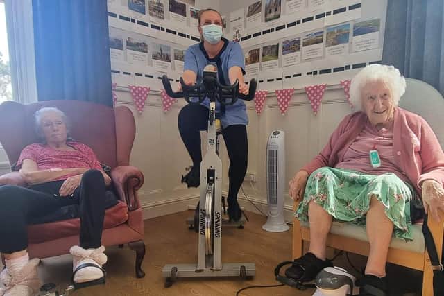 Pauline Poore and Audrey Jenney clocking up the miles while sitting in their chairs and encouraging Karen Burman to just keep peddling.