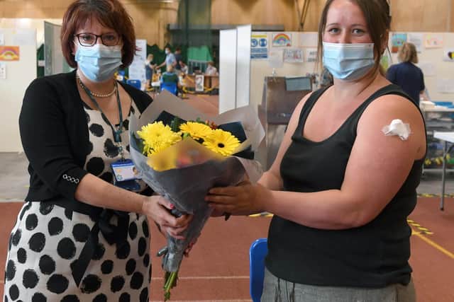 Rebecca Neno presents Ruth Granby with a bouquet of flowers after she became the 500,000th person to receive the first vaccination in Lincolnshire