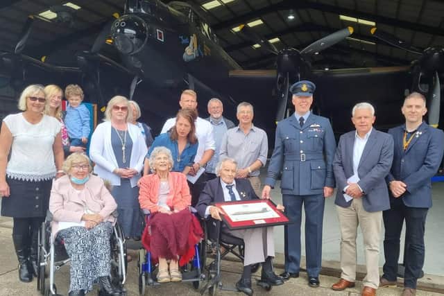 Fred Pearce (centre) celebrating his 100th birthday in the shadow of the Lancaster with 207 Squadron Wing Commander Scott Williams (right) , of RAF Marham, family and friends.