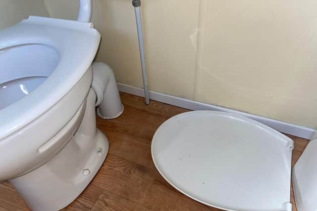 A broken toilet seat was left on the floor.