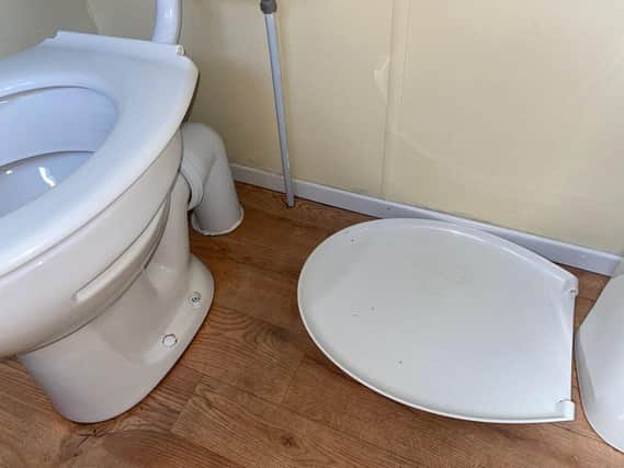 A broken toilet seat was left on  the floor.
