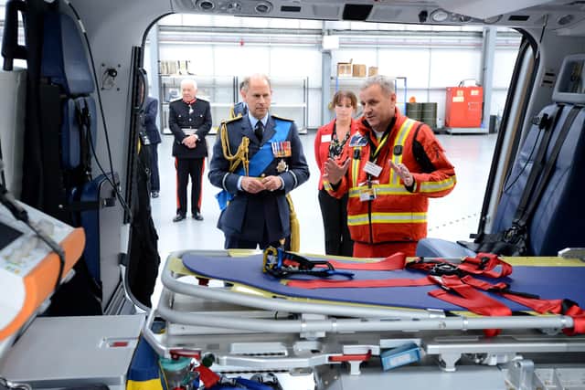 The Earl of Wessex is given a guided tour of the helicopter by Medical Director Gareth Davies. EMN-210930-093045001