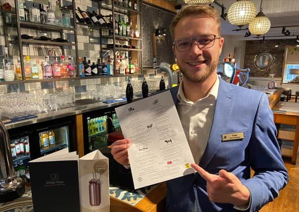 General manager at the White Hart Hotel Dominic Solesbury with a menu and its offer of ‘Invisible Chips’.