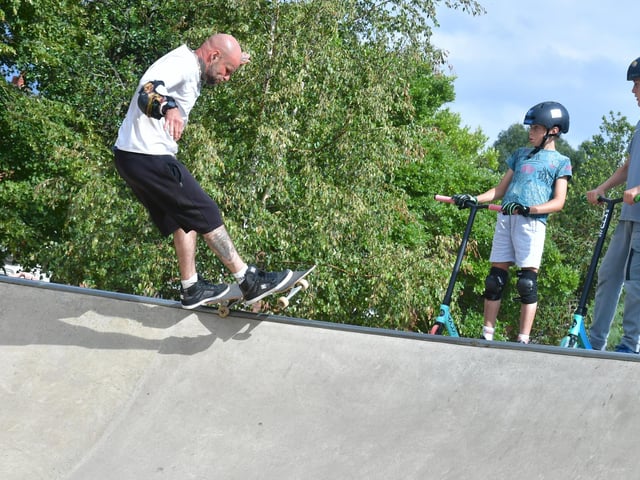 Scooter riders watch some skateboarding skills.