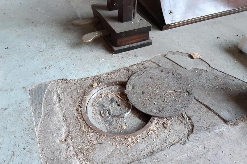 Shane initially thought this circular piece of metal on the floor would reveal access to a water isolation valve. Instead, he found it was hiding a floor safe.