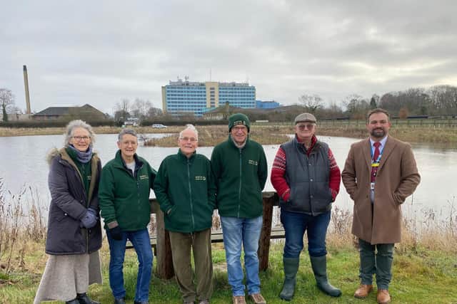 The group on the edge of the lake with Pilgrim Hospital in the background.
