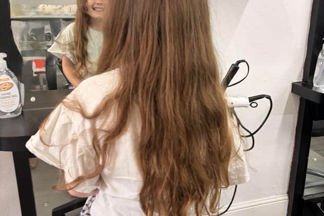 Before the chop! Maeve excitedly awaits the cutting to begin in the salon.