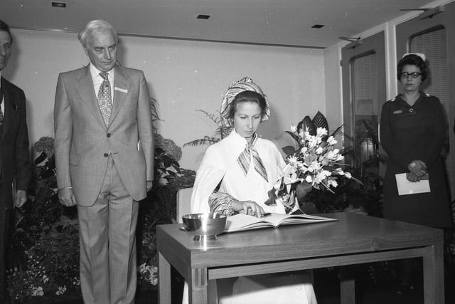 Princess Anne signs the visitors' book. She is pictured with a silver bowl, presented to her by David Thomas, chairman of the Lincolnshire Area Health Authority, and a bouquet of flowers, presented by sister N. Barker, a long-serving member of staff.