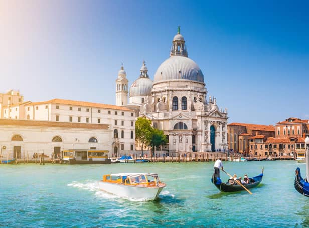 Beautiful view of traditional Gondola on Canal Grande with historic Basilica di Santa Maria della Salute in the background on a sunny day in Venice, Italy