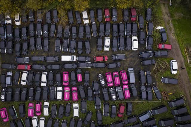 A staff member walks through unused black cabs parked in a large area of farmland in Epping Forest, which is being rented by GB Taxi Services to store their large fleet of London taxis that are no longer being used due to a severe drop in demand as coronavirus restrictions continue to reduce travel and office working.