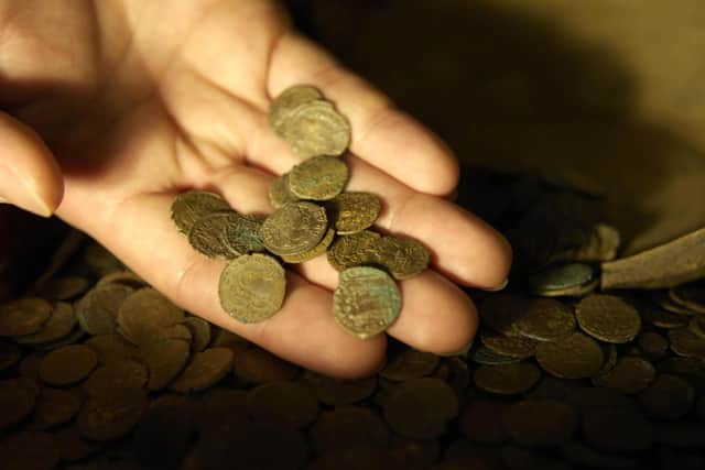 Part of a Roman coin hoard found in Snodland in north Kent is looked at closely by a British Museum worker; the coin hoard, discovered by a digger driver, is made up of over 3,600 coins and is part of the British Museum's annual report of treasure finds at the British Museum in London.
