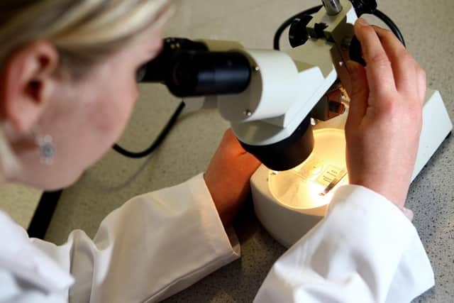 File photo dated 19/05/08 of a woman looking through a microscope. Unravelling the genetic codes of all children with cancer could lead to improved diagnosis and treatment, scientists have said. A pilot study at Addenbrooke???s Hospital in Cambridge saw researchers examine the whole genome of a small number children with "solid" cancers. Issue date: Monday November 8, 2021.