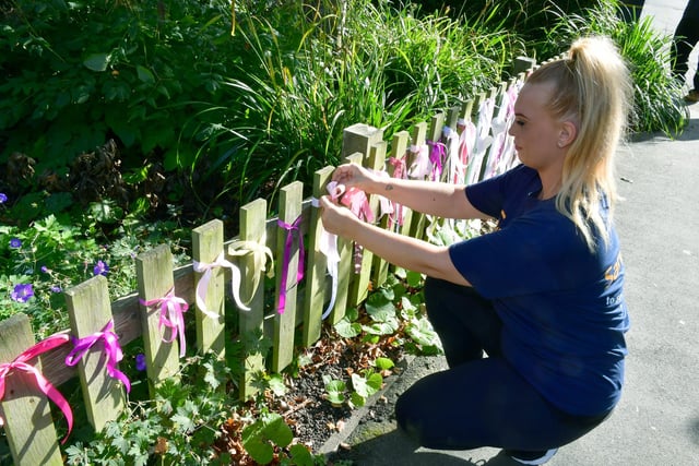 Shinead Dunne ties a ribbon to the fence along the walkway.