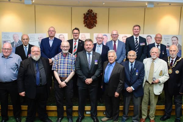 Leader of NKDC Coun Richard Wright and chairman Coun Mike Clarke with the 13 veterans who received badges for their service.
