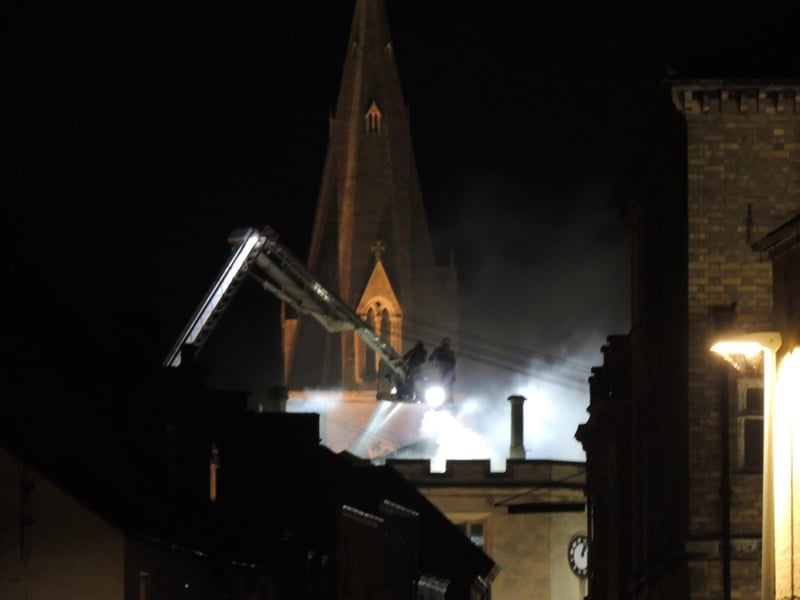 Firefighters work on, silhouetted against St Denys' Church. Photo: Andy Hubbert
