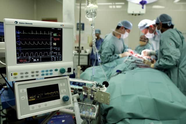 Surgeons carry out an operation to remove a tumour from a patient at an NHS hospital.