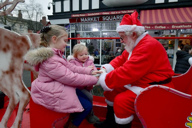 From left - Maisie Burrows, five, and Hattie Burrows, two, with Santa on the Rotary Club of Sleaford sleigh.
