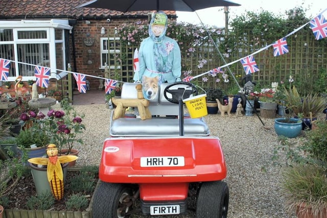 A cheeky scarecrow of the Queen riding a quadbike with a collection bucket.