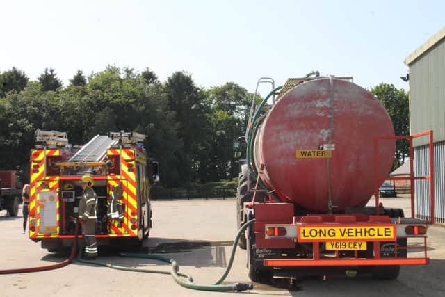 A fire engine hooked up to a tanker using a hose and an innovative adapter coupling that allows firefighters access to on farm water supplies