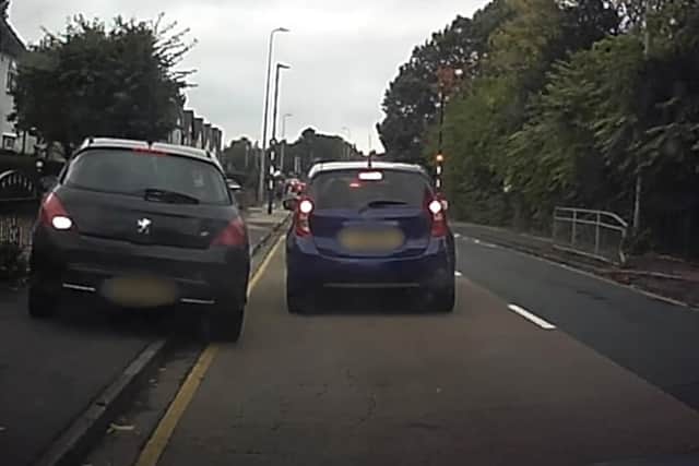 A still from Operation Snap footage showing a car driving up a footpath attempting to undertake another vehicle.