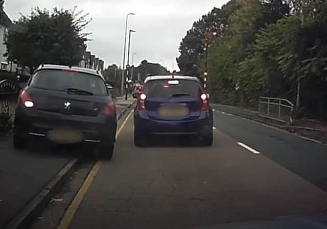 A still from Operation Snap footage showing a car driving up a footpath attempting to undertake another vehicle.