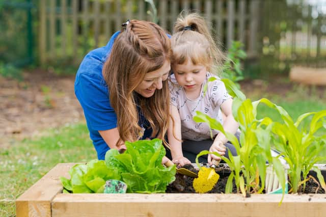 Nursery practitioner Beth Cooper pictured harvesting some vegetables from the Owl Garden with one of the pupils.