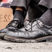 Homeless man sitting on the street near the sign. Photo: Getty Images/iStockphoto