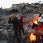 Survivors gather next to a bonfire outside collapsed buildings in Kahramanmaras, after their homes were destroyed in a 7.8 magnitude earthquake which struck the border region of Turkey and Syria on February 6. (Photo by ADEM ALTAN/AFP via Getty Images)