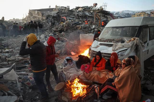 Survivors gather next to a bonfire outside collapsed buildings in Kahramanmaras, after their homes were destroyed in a 7.8 magnitude earthquake which struck the border region of Turkey and Syria on February 6. (Photo by ADEM ALTAN/AFP via Getty Images)
