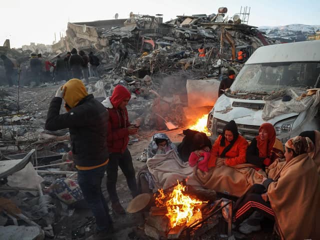 Survivors gather next to a bonfire outside collapsed buildings in Kahramanmaras, after their homes were destroyed in a 7.8 magnitude earthquake which struck the border region of Turkey and Syria on February 6. (Photo by ADEM ALTAN/AFP via Getty Images)