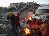 Survivors gather next to a bonfire outside collapsed buildings in Kahramanmaras, after their homes were destroyed in a 7.8 magnitude earthquake which struck the border region of Turkey and Syria on February 6. (Photo by ADEM ALTAN/AFP via Getty Images)