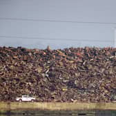 A vehicle passes a towering pile of scrap metal at Southampton port.