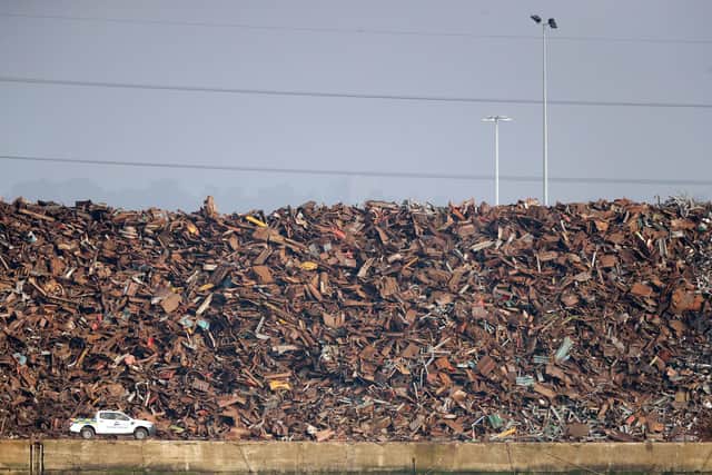 A vehicle passes a towering pile of scrap metal at Southampton port.