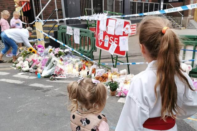 Young children from the local community visit the site of the floral tributes left in Fountain Lane.