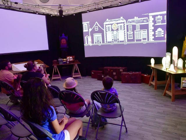 Enthralled audiences watch 'The Flight Of Millicent Stanley', an immersive animation, within Jubilee Park's white dome.