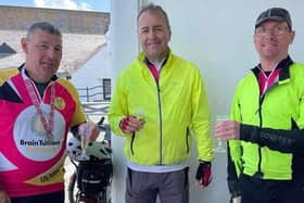 Ed Cox (right) and cycling friends Jon Silver and Adam Sessions toast the completion of their challenge with champagne in Land's End.