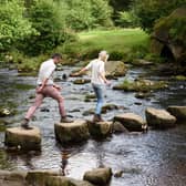 Visitors crossing stepping stones at Hardcastle Crags, West Yorkshire. Hardcastle Crags is a beautiful wooded valley with deep ravines, tumbling streams and glorious waterfalls.